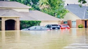Image of a Flooded Street with cars and houses in the background under water